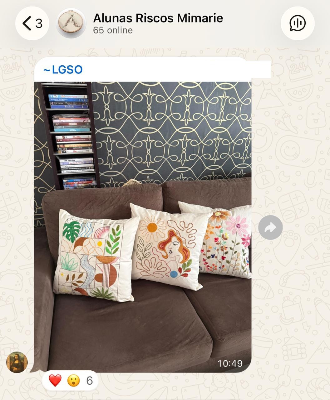 Três almofadas bordadas por aluna, no sofá